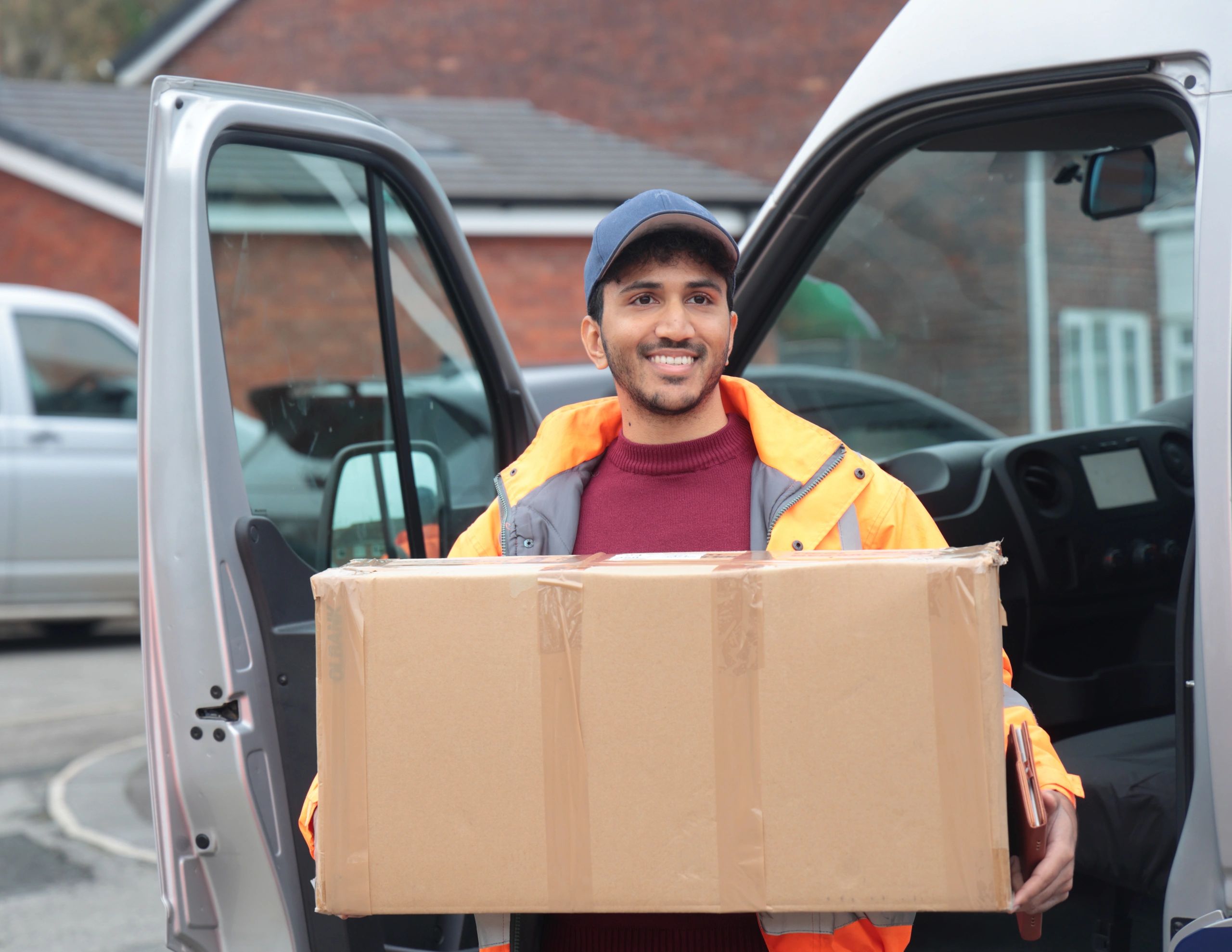 Delivery driver carrying boxes near a delivery van